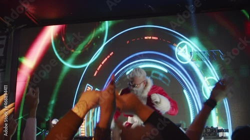 DJ Santa Claus playing music at nightclub and enjoying great festival party. photo