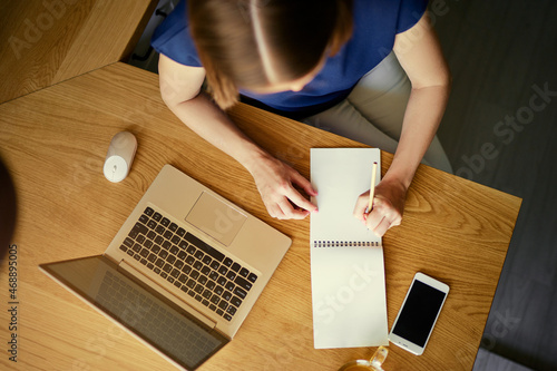 Ideas for business. Studying and working. Freelance concept. Top view of woman making notes using laptop.