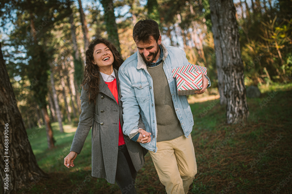 Young beautiful couple taking walk after exchanging christmas gifts in the nature smiling and laughing. Young beautiful couple taking walk after exchanging christmas gifts in the nature smiling and laughing.