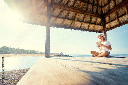 Relaxed and cheerful. Work and vacation. Outdoor portrait of happy young woman using tablet computer on terrace near the sea.