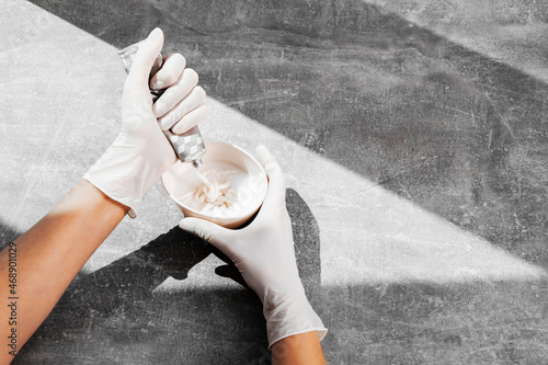 a girl in white protective gloves squeezes hair dye into an oxidizer. colorist at work close-up hair care hair mask hair dye