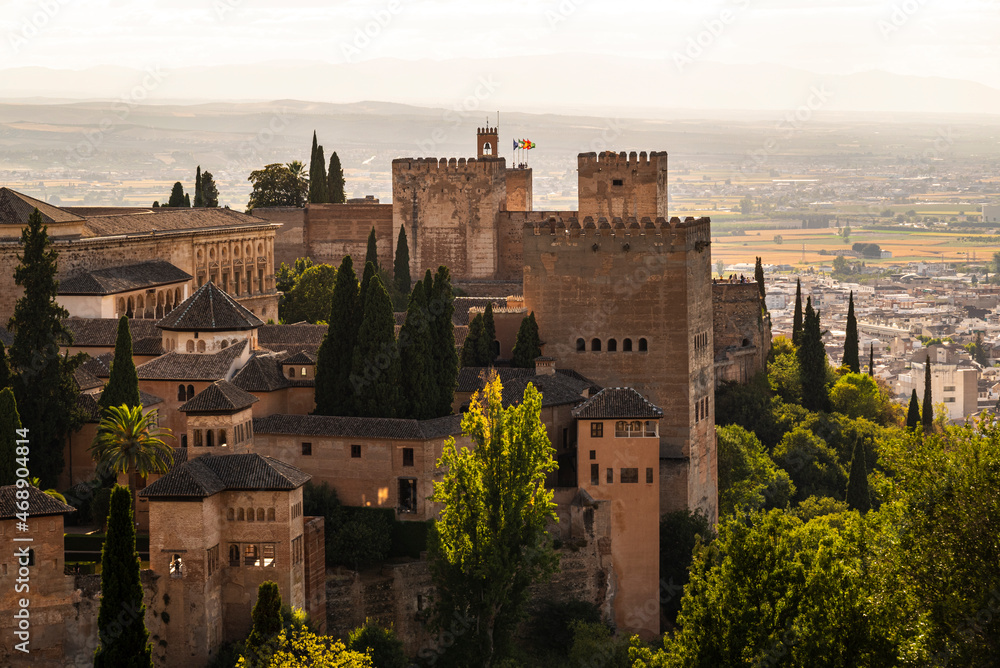 The Nasrid fortification of the Alhambra de Granada with the towers of the Nasrid Palaces, the Alcazaba fortress and the Palace of Charles V in beautiful evening light, Granada, Andalusia, Spain