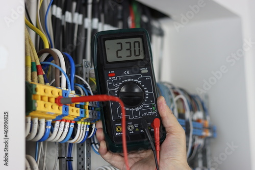 An electrical engineer uses a multimeter to check the electrical parameters in the control panel for process control.