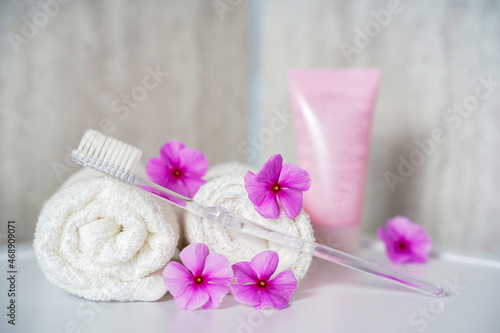 Toothbrush, toothpaste and white towels, pink flowers aromatherapy. Oral care, body hygiene and morning daily routines.