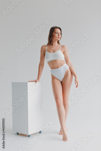 girl gymnast, in a white uniform, panties and top, in the studio on a white background shows exercises