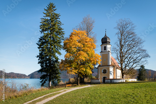 Die barocke Kirche St. Margareth auf der Halbinsel Zwergern im Walchensee mit herbstlich gefärbten Bäumen, Bayern, Deutschland photo