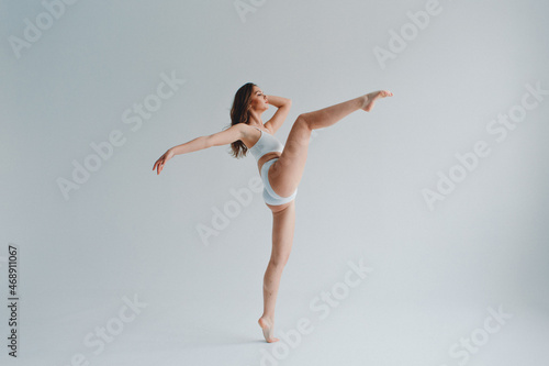 girl gymnast, in a white uniform, panties and top, in the studio on a white background shows exercises