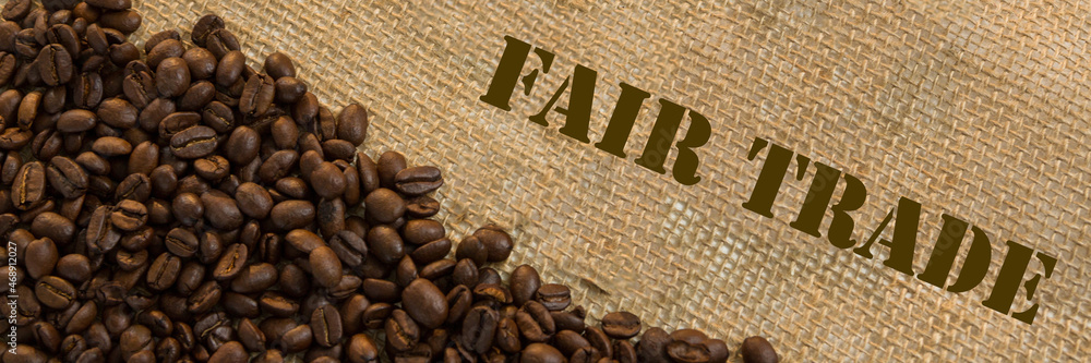 Dark roasted fair trade coffee beans with text Fair Trade. Panoramic image Dark roasted fair trade coffee beans with text Fair Trade. Panoramic image