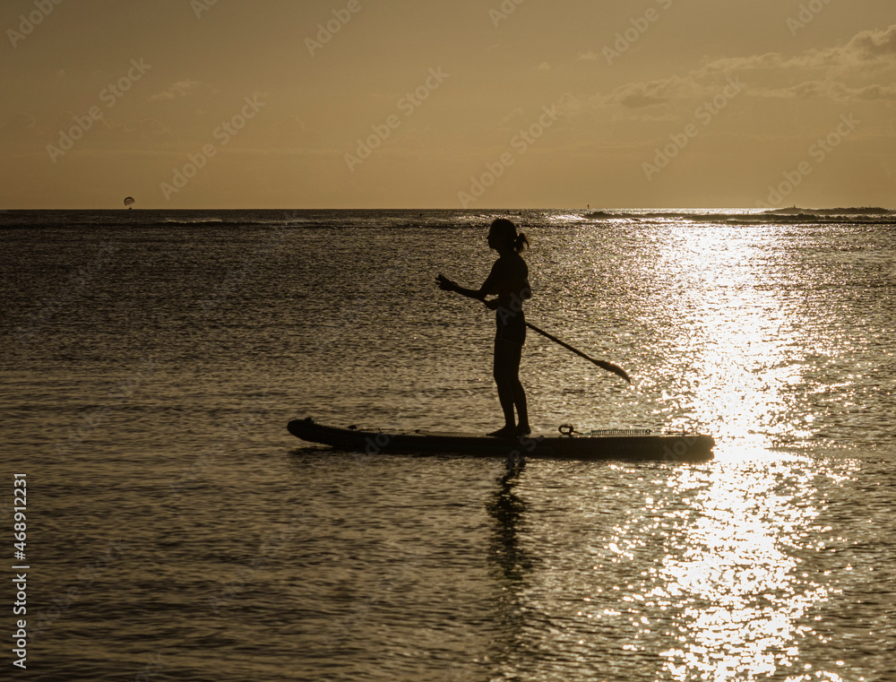 Paddle boarder at sunset on Oahu, Hawaii.