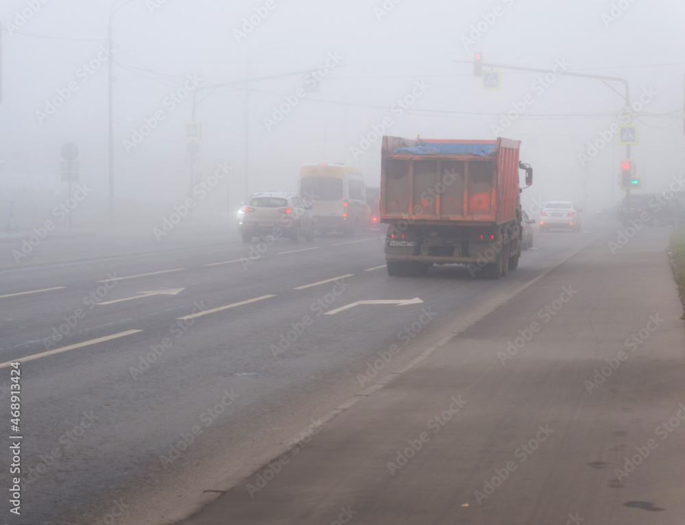 Cars drive in fog on city roads