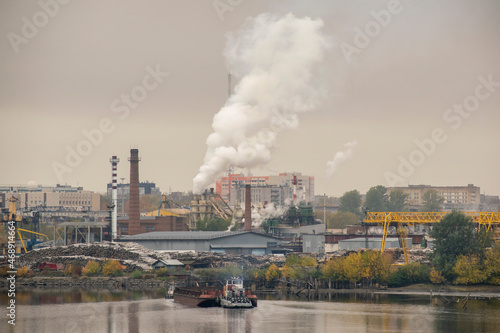 Woodworking factory on the river. The barge is mooring for loading. Industrial concept. © Ilia Petukhov
