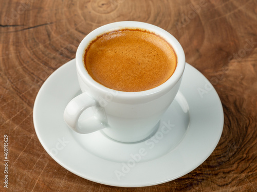 frothy coffee in white cup wood background