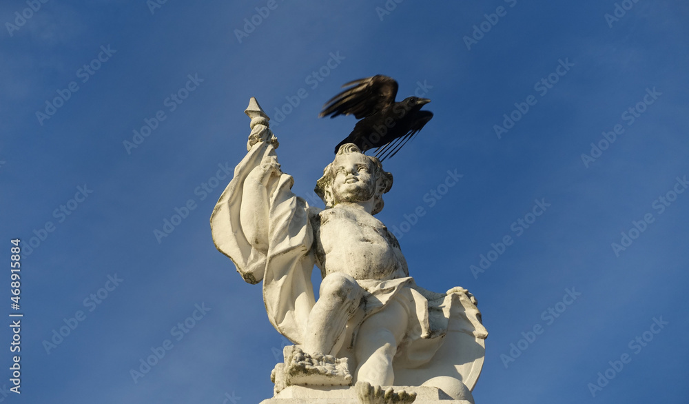 Ein Rabe fliegt von einer mythologischen Figur am Karlsruher Schloss Ein Rabe fliegt von einer mythologischen Figur am Karlsruher Schloss
