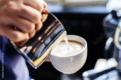 Making cappuccino. The process of pouring milk from a metal mug into a cup. Close-up. Unrecognizable person © Dmitry