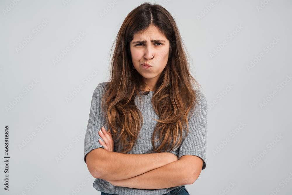 Fototapeta premium Portrait of funny frustrated naughty woman looking at camera with comical resentful unhappy face expression. Indoor studio shot isolated on white background