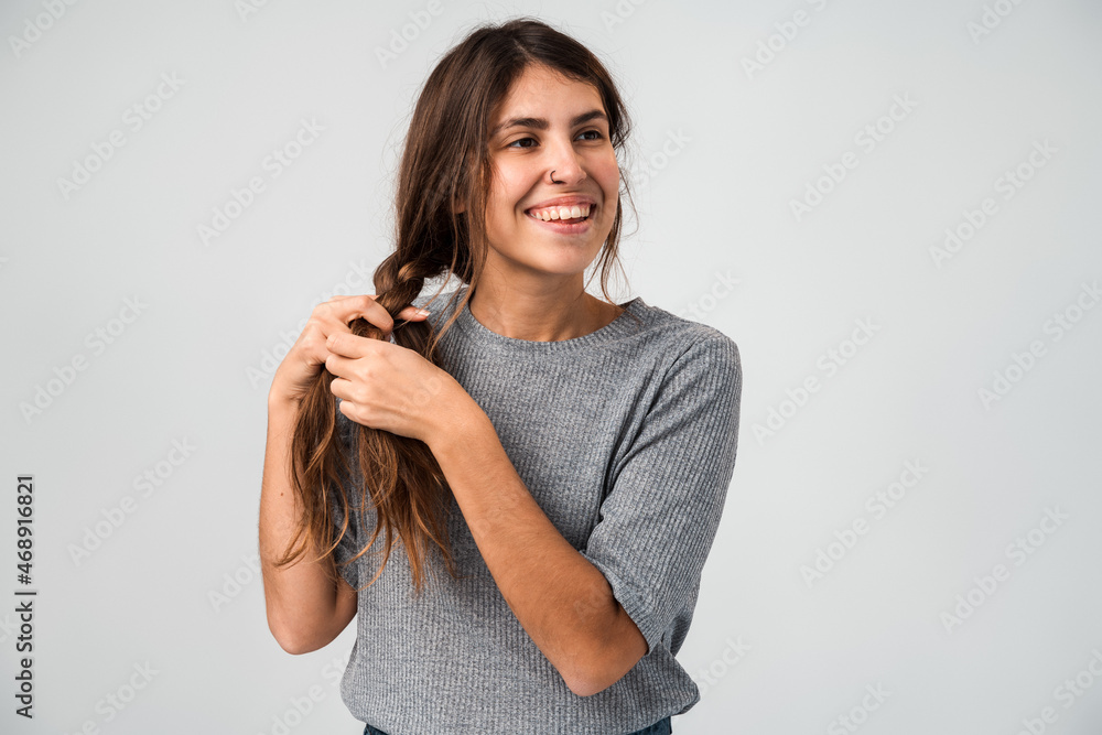 Waist up portrait view of the overjoyed woman making braids with toothy smile isolated on a white background. People appearance concept Waist up portrait view of the overjoyed woman making braids with toothy smile isolated on a white background. People appearance concept
