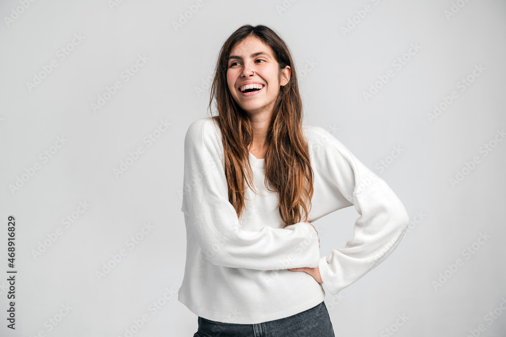 Portrait of happy lively young beautiful hipster woman standing and looking away with toothy smile. Indoor studio shot isolated on white background Portrait of happy lively young beautiful hipster woman standing and looking away with toothy smile. Indoor studio shot isolated on white background
