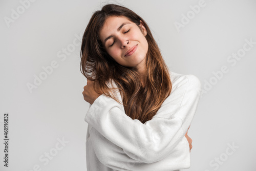 I love myself. Portrait of self-satisfied egoistic woman in urban style embracing herself and smiling with pleasure, feeling self-pride. Studio shot isolated on white background