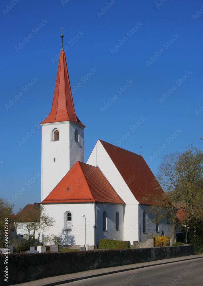Medieval village church of St Leonhard with its gothic tower, its red tile roof and a cemetery in Burgoberbach, Franken region in Germany