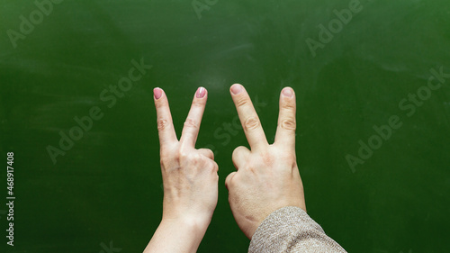 Male and female hand pointing fingers gesture goat on the background of the blackboard.