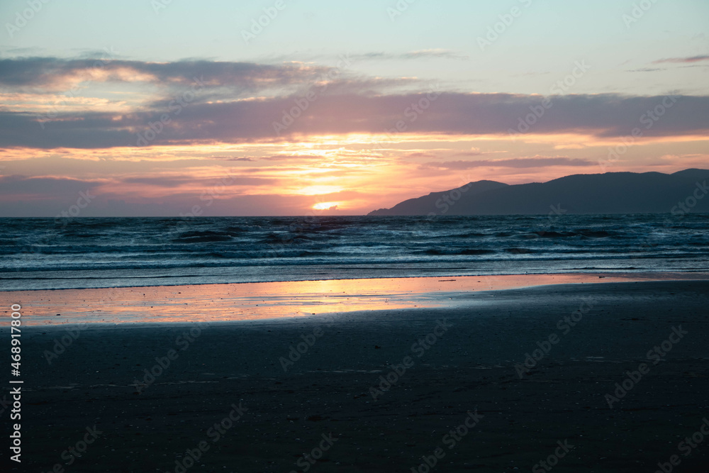 Atardecer en la playa con el reflejo del sol en la arena de Nueva Zelanda Atardecer en la playa con el reflejo del sol en la arena de Nueva Zelanda