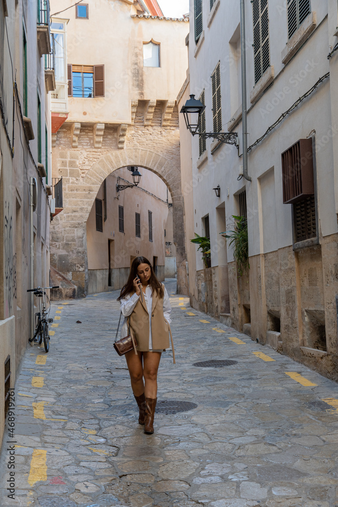 mujer hermosa con vestido marrón hablando por teléfono por una calle en el centro de Palma de Mallorca