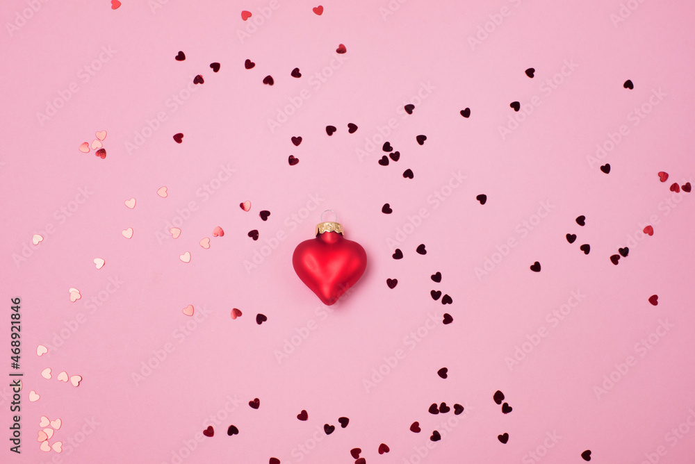 Red confetti in the form of hearts on a pink background and Decoration Valentines day backdrop Flat lay style with minimalistic design Template for banner or party invitation