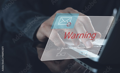 Blocking spam e-mail, warning pop-up for phishing mail, network security concept. Business man working on laptop computer at home with warning window