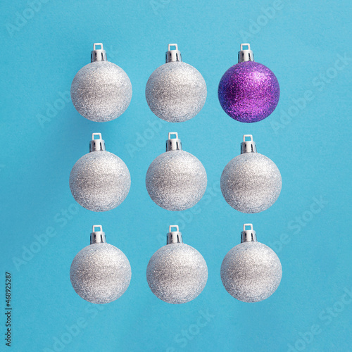 metallic silver shiny baubles pattern with one vivid violet.Holidays celebration Christmas concept.Minimal New Year decoration flat lay