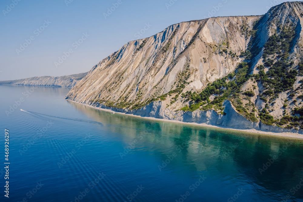 Coastline with quiet sea and cliff with trees. Summer on sea and boat. Aerial view