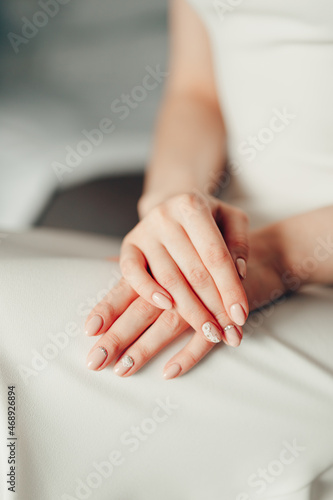 Bride in the white dress crossed her hands in her lap. Half-portrait
