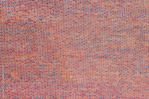 A wide brick blank wall of an old building. Uneven brickwork on a large wall.