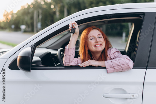 Woman got driver's license. Joyful female sitting in new car and shows keys.