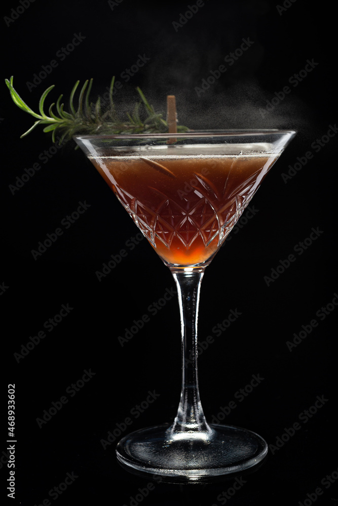Alcoholic cocktail Cosmopolitan cocktail decorated with rosemary on martini glass and spray  on black background. Copy Space.