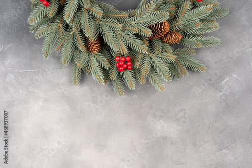 Christmas wreath with assorted evergreen boughs on gray concrete wall.