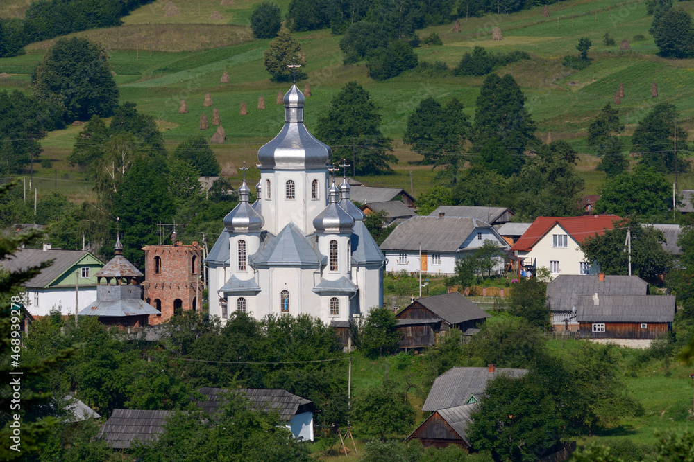 Carpathian village: catholic church, country houses, gardens and hill. Lugi village, Ukraine