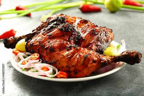 Homemade traditional Indian tandoori chicken  served in plate with fresh salads. 
