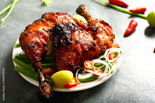 Homemade traditional Indian tandoori chicken  served in plate with fresh salads. 