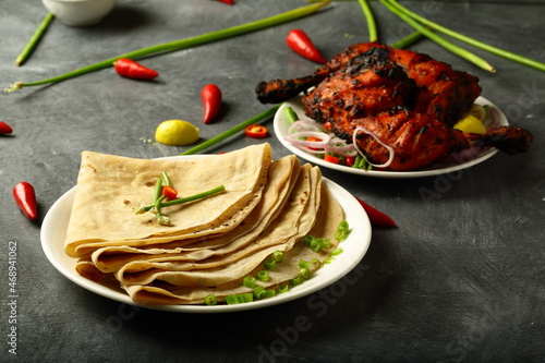 Healthy Indian meal-  whole wheat chapattis served with grilled chicken on a rustic kitchen table. photo