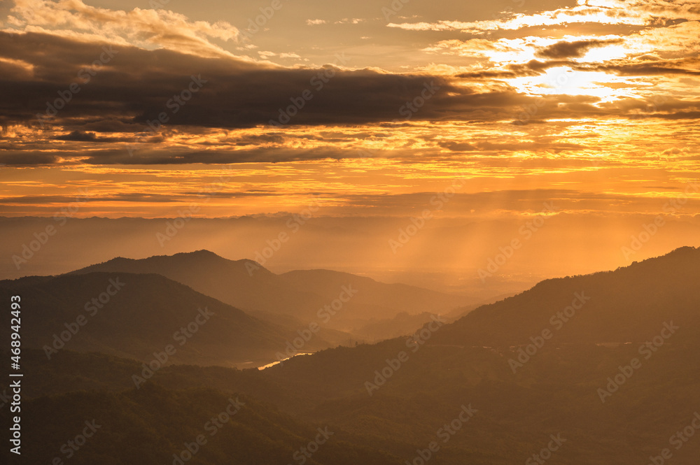 Beautiful mountain landscape at sunrise sky with clouds in sunlight.