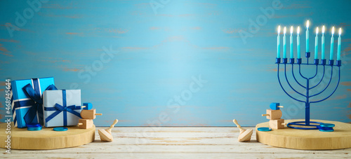 Fototapeta kuchenna Jewish holiday Hanukkah banner design with menorah and gift box on wooden table over blue background