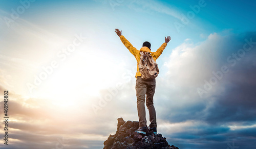 Man traveler on mountain summit enjoying nature view with hands raised over clouds - Sport, travel business and success, leadership and achievement concept photo