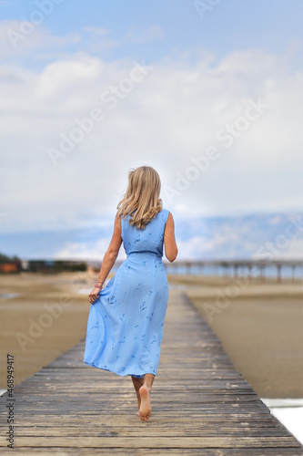 Beautiful blonde woman posing on an empty sea beach photo