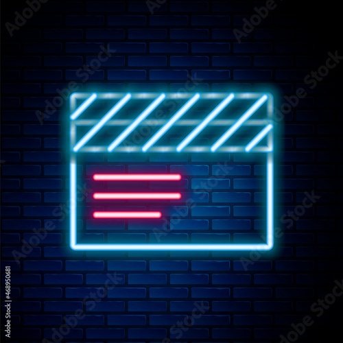 Glowing neon line Movie clapper icon isolated on brick wall background. Film clapper board. Clapperboard sign. Cinema production or media industry. Colorful outline concept. Vector