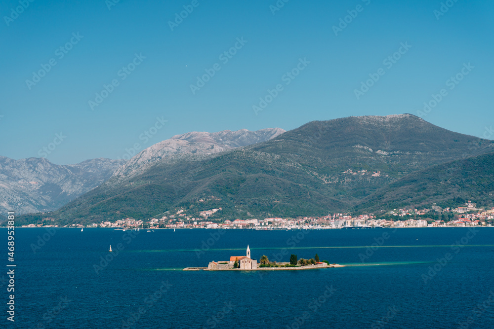 Island of Otocic Gospa in the bay against the backdrop of the town on the coast. Montenegro