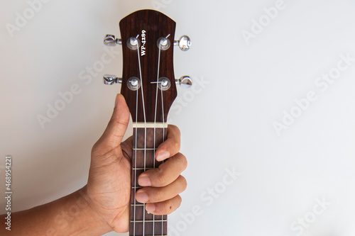 hand hold neck of ukulele it for playing on white background