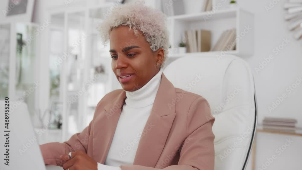 Attractive African American woman leans back in office chair pulling up ...