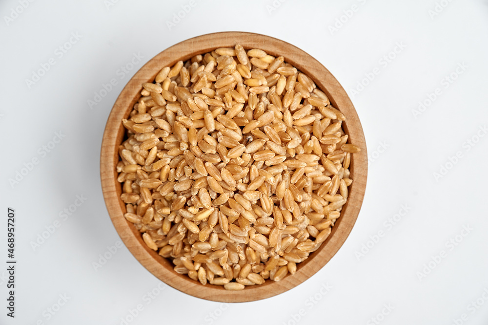 peeled wheat grain in a wooden bowl on a white background peeled wheat grain in a wooden bowl on a white background