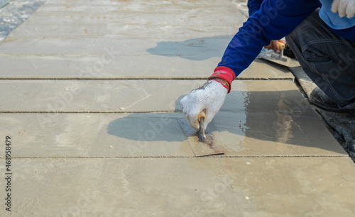 Motion blur white cloth gloves of workers are holding the trowel to smooth the cement face on floor in construction area.
