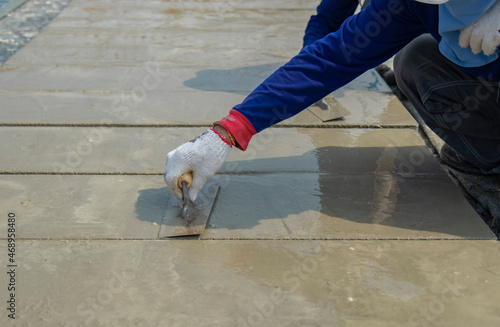 Motion blur white cloth gloves of workers are holding the trowel to smooth the cement face on floor in construction area.